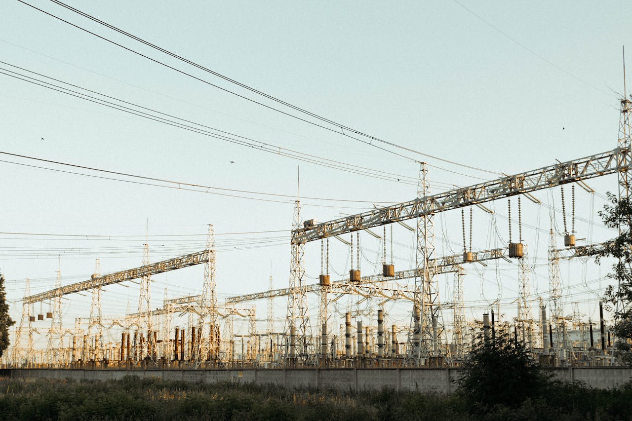 A wide view of an industrial electrical substation with power lines and towers outdoors.